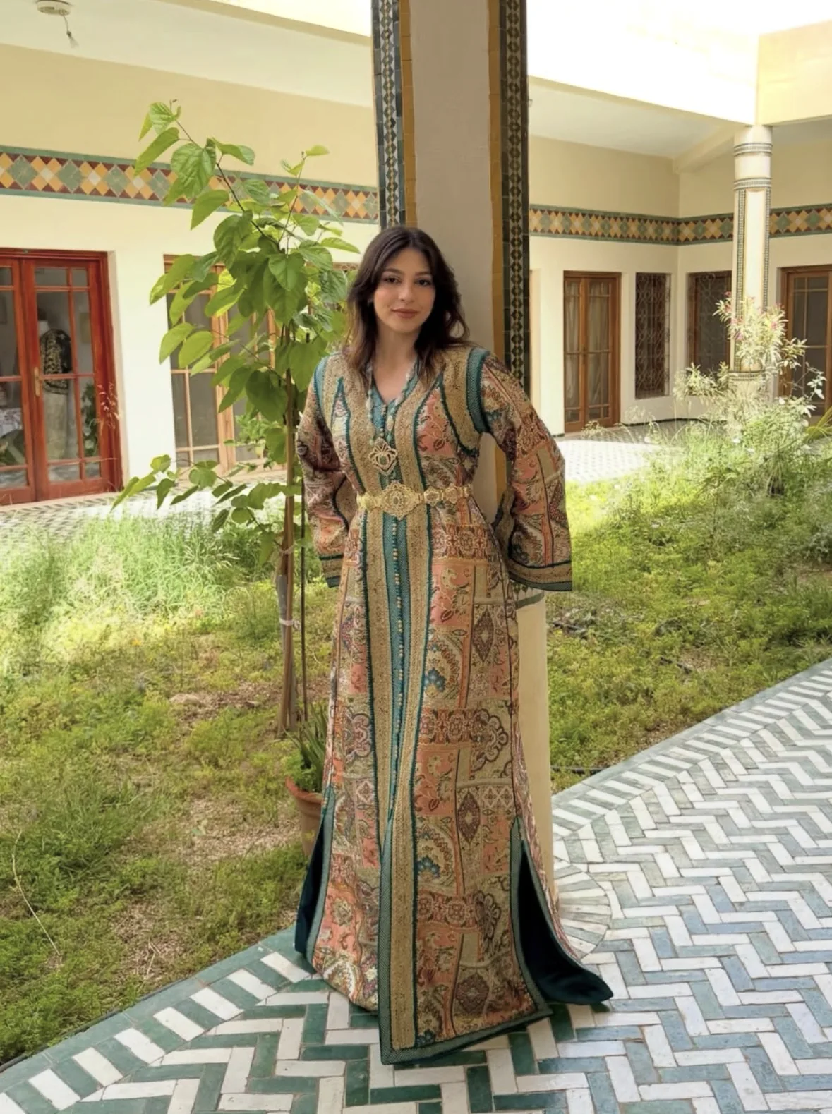 Caftan imprimé cachemire aux tons corail et vert, porté dans un riad d'Oujda
